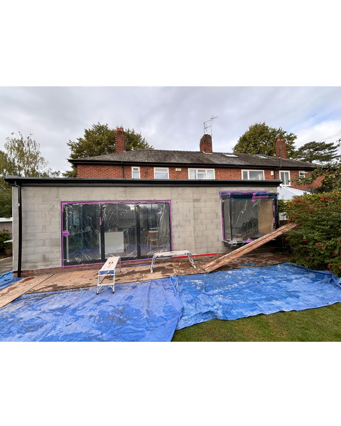 Rear extension in bare grey blockwork before rendering, with plastic masking the windows