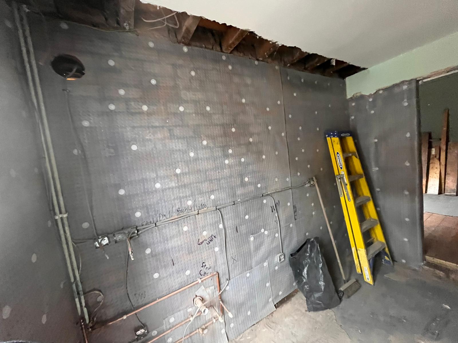 Damp-proof membrane installed across walls with exposed ceiling joists