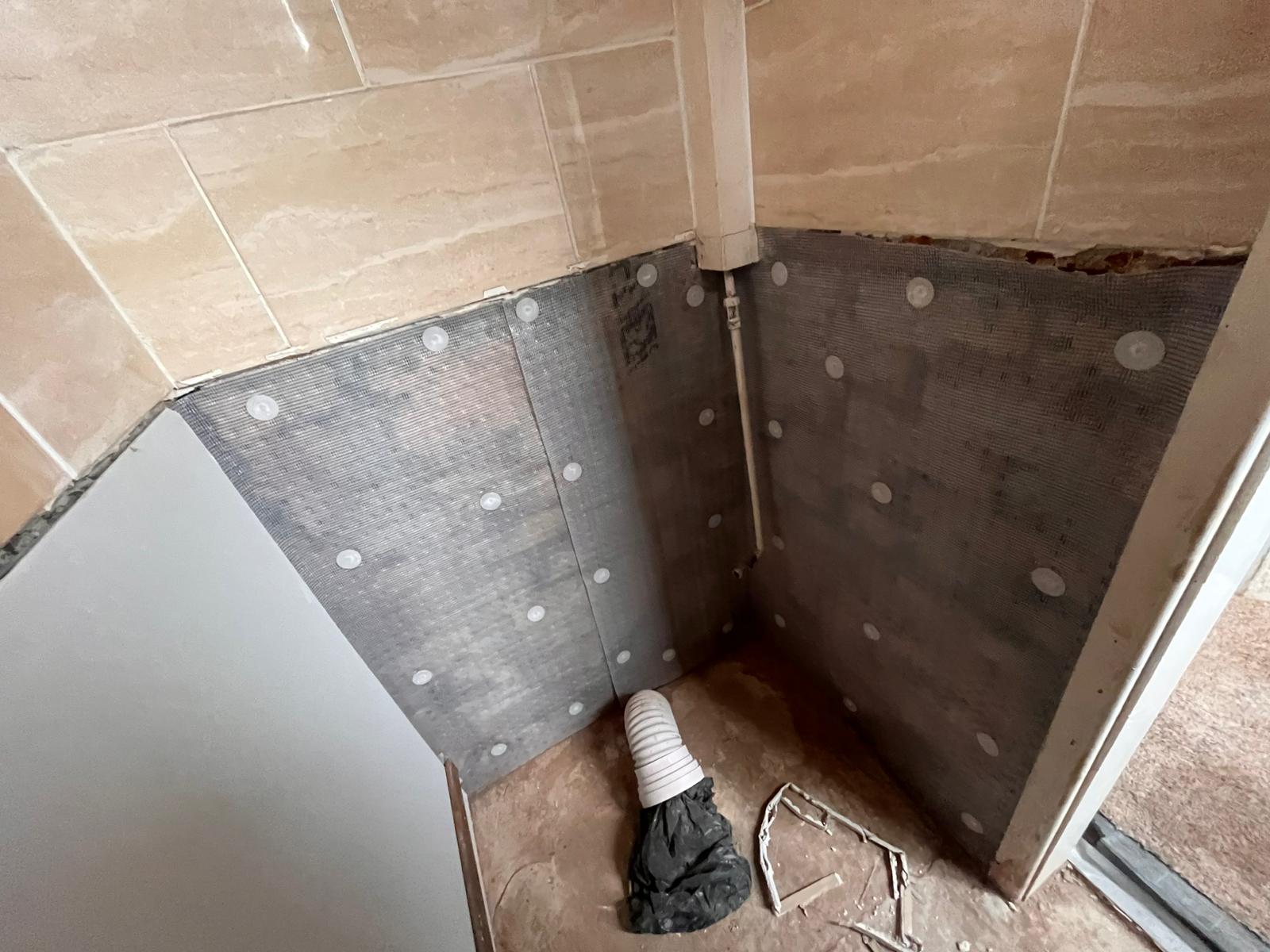 Bathroom corner with damp-proof membrane installed below existing tiles