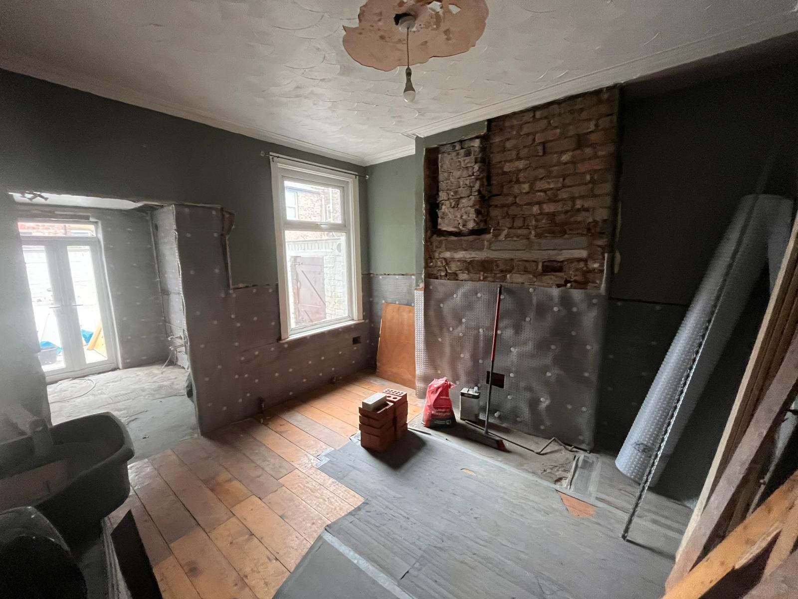Damp room with half-installed membrane and exposed chimney brickwork