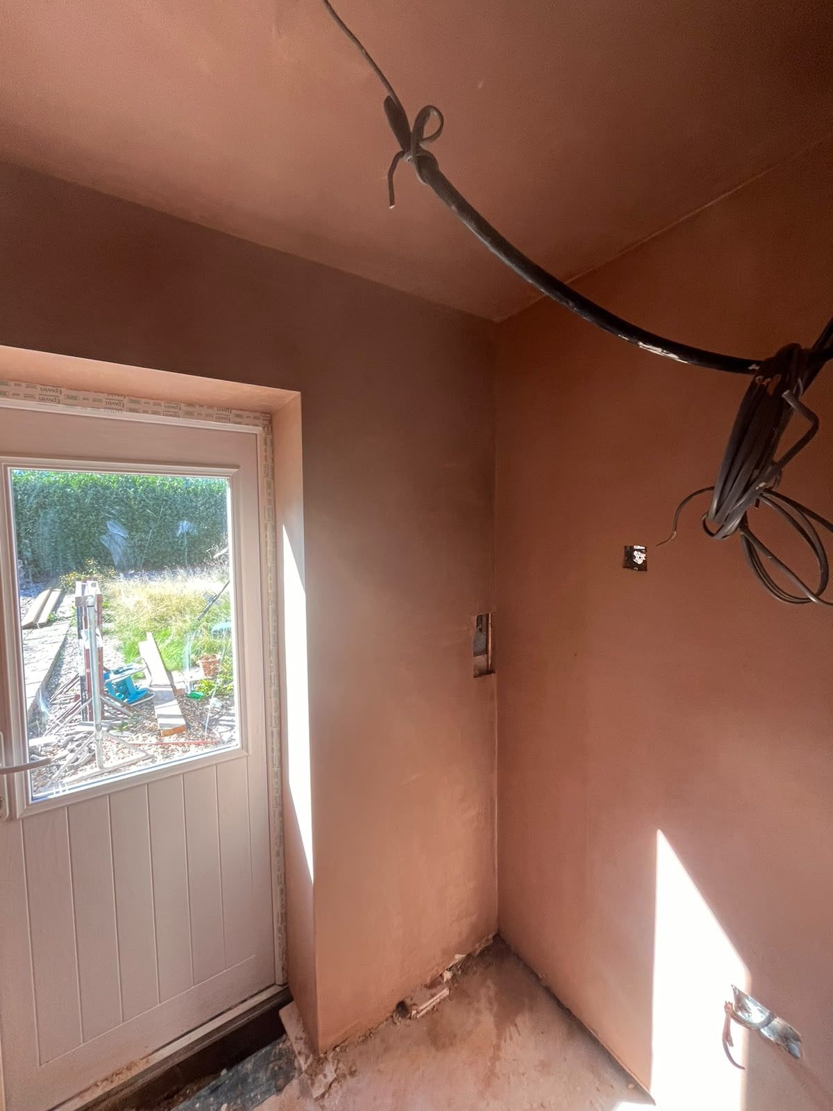 Corner beside the back door skimmed with cables ready for second fix