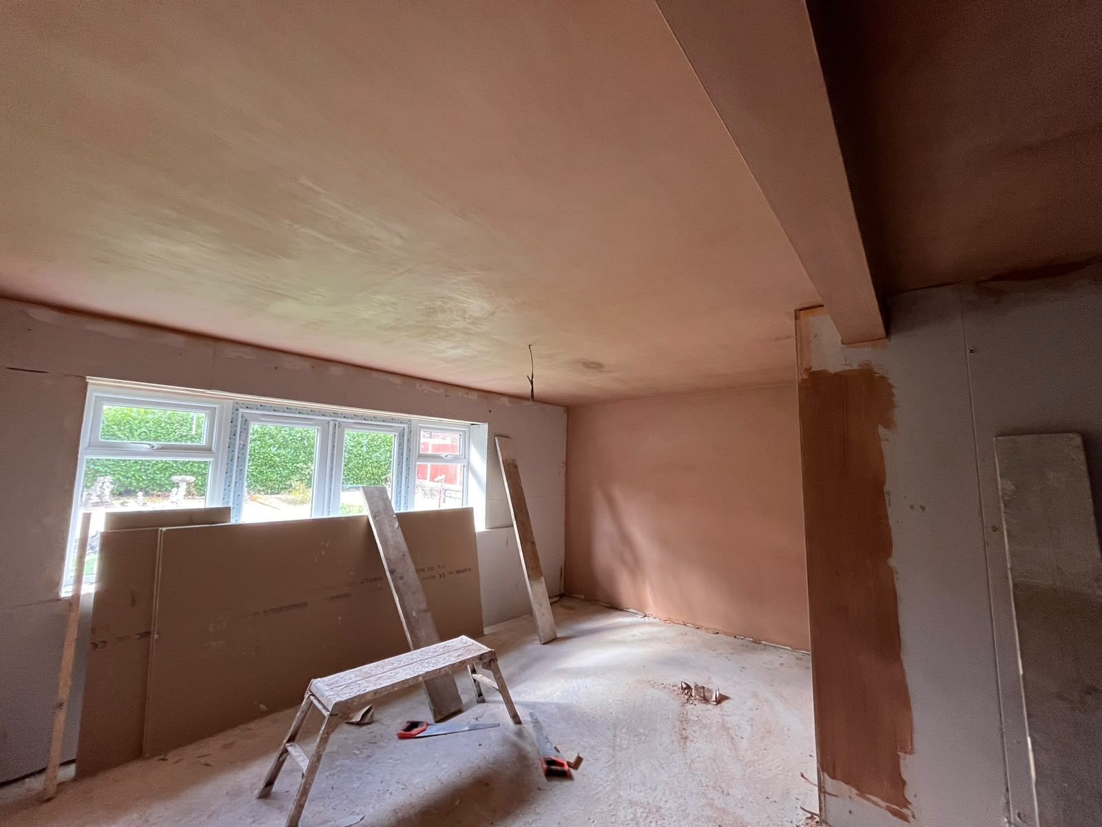 Front room freshly skimmed with bay window and new plasterboard stacked ready
