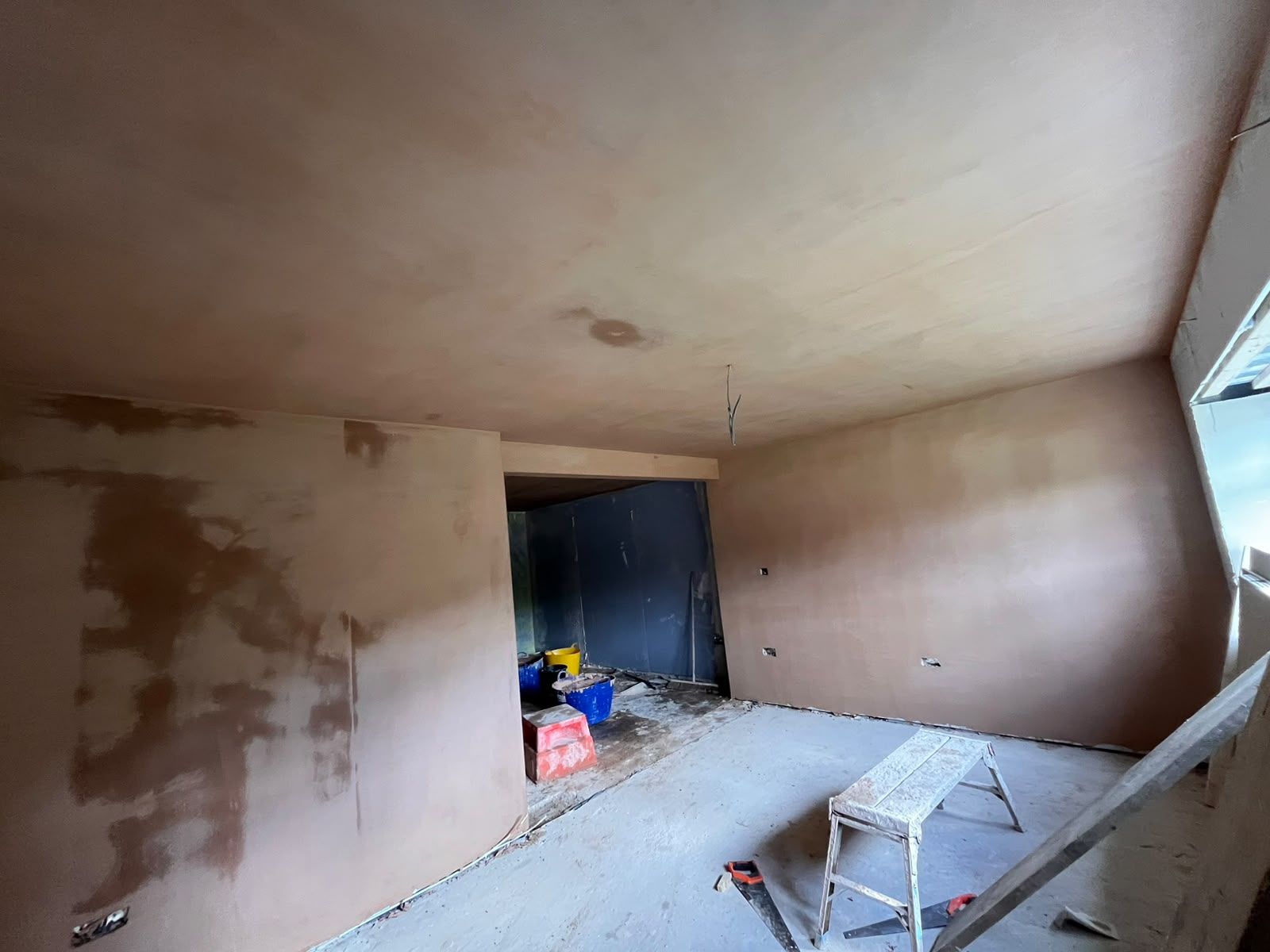 Open-plan room with new skim drying out on walls and ceiling