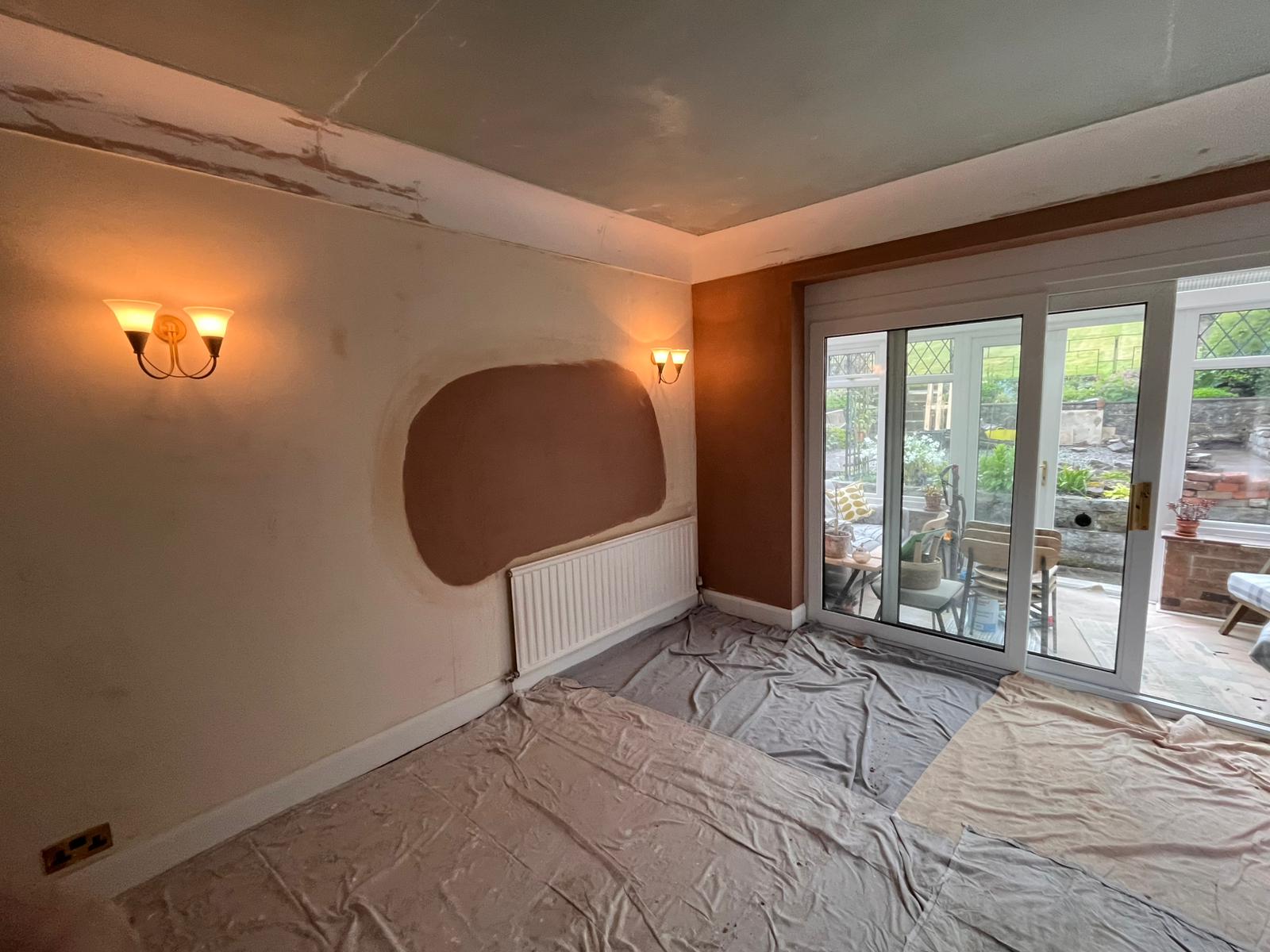 Wall light glowing in living room with oval plaster patch over chimney area